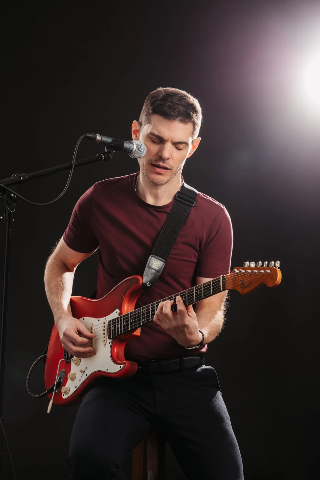 George Kramer singt am Mikrofon und spielt eine rote Fender Stratocaster.